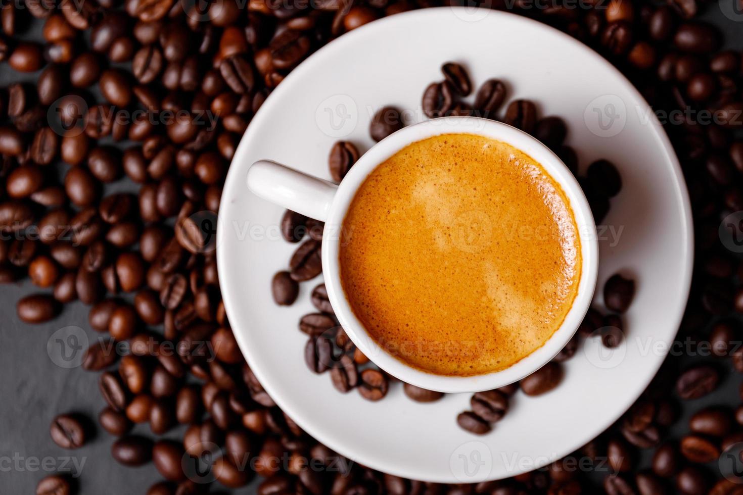 Hot fresh black coffee with milk foam for morning menu in white ceramic cup with coffee beans roasted on. photo