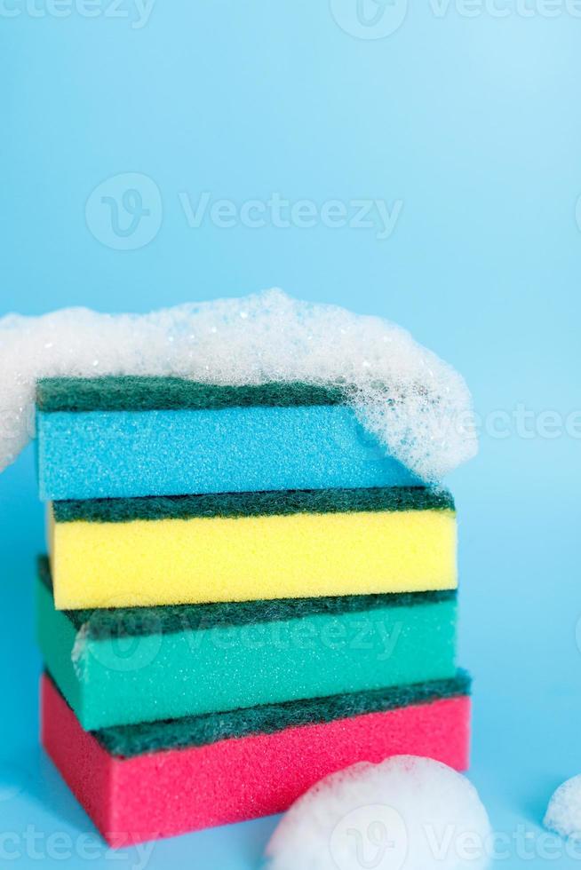esponjas multicolores para limpiar sobre un fondo azul. espacio para texto. foto