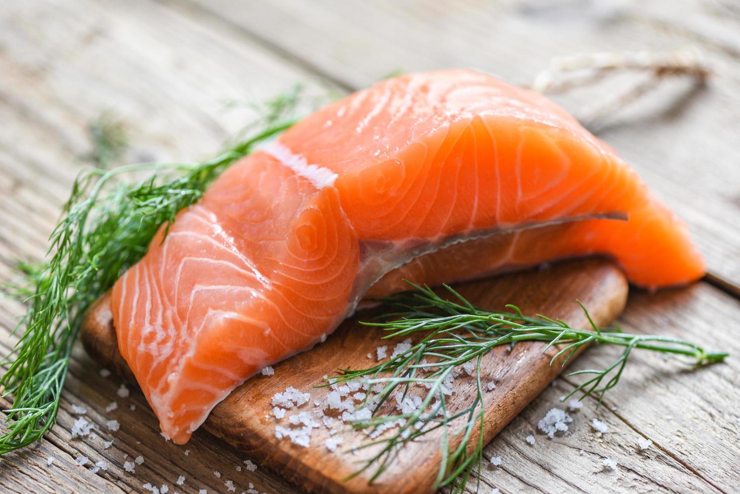 Raw salmon filet with herbs and spices on wooden background photo