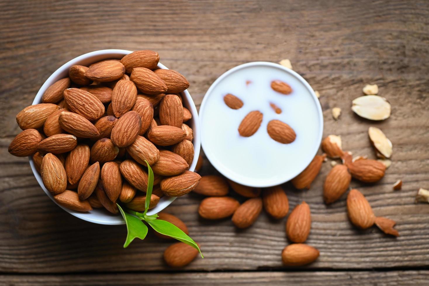 leche de almendras y nueces de almendras sobre fondo de madera, deliciosas almendras dulces en la mesa, nuez de almendras tostadas para comida saludable y bocadillos - vista superior foto