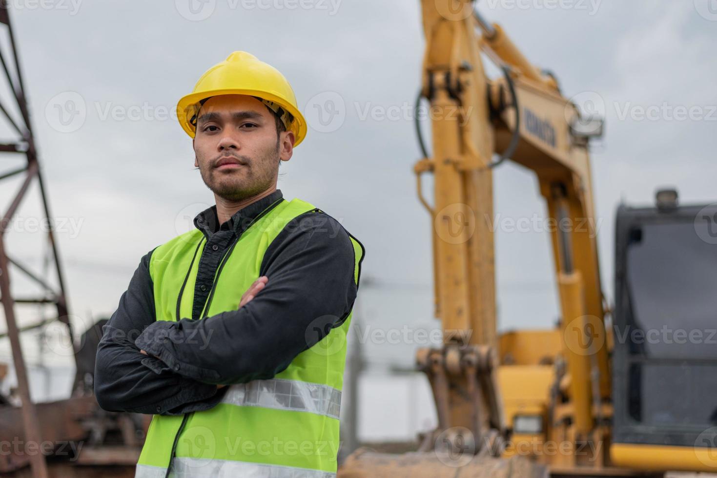 engineer man working in building site. Asian worker man standing and crossed arms in construction site. photo