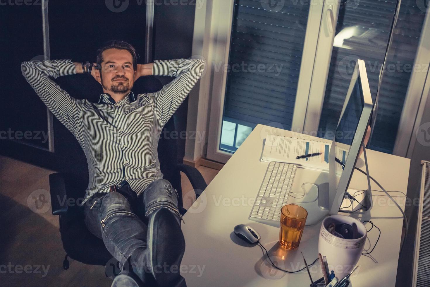 Happy businessman relaxing after working day in the office. photo