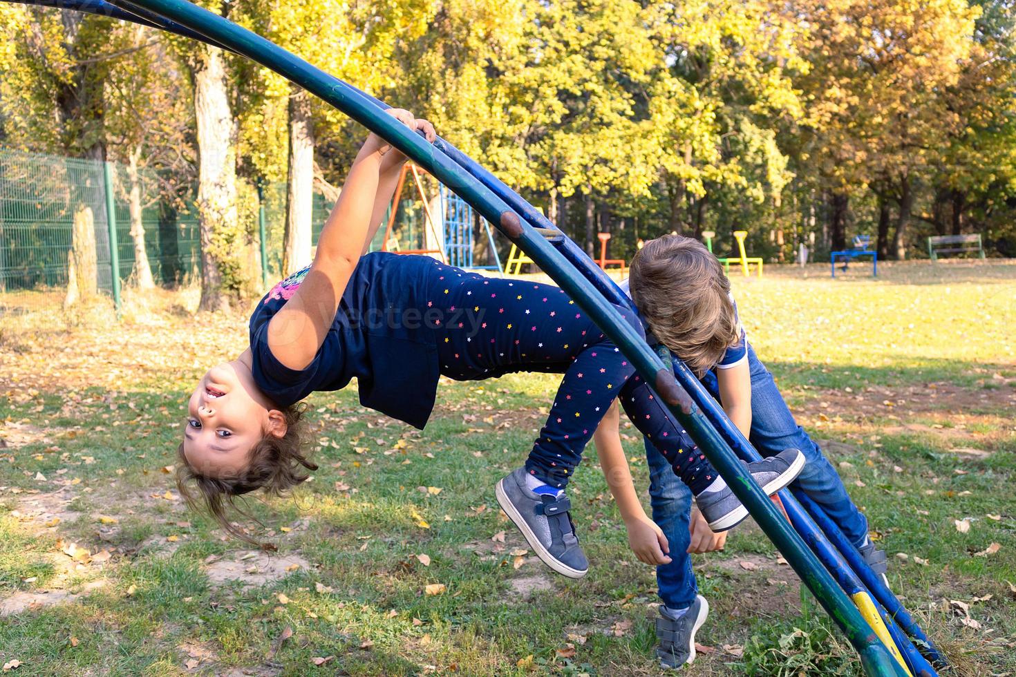 Small girl and boy playing at the playground in nature. photo