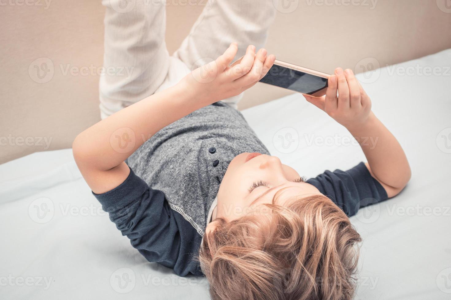 Playful boy in pajama taking selfie with smart phone. photo
