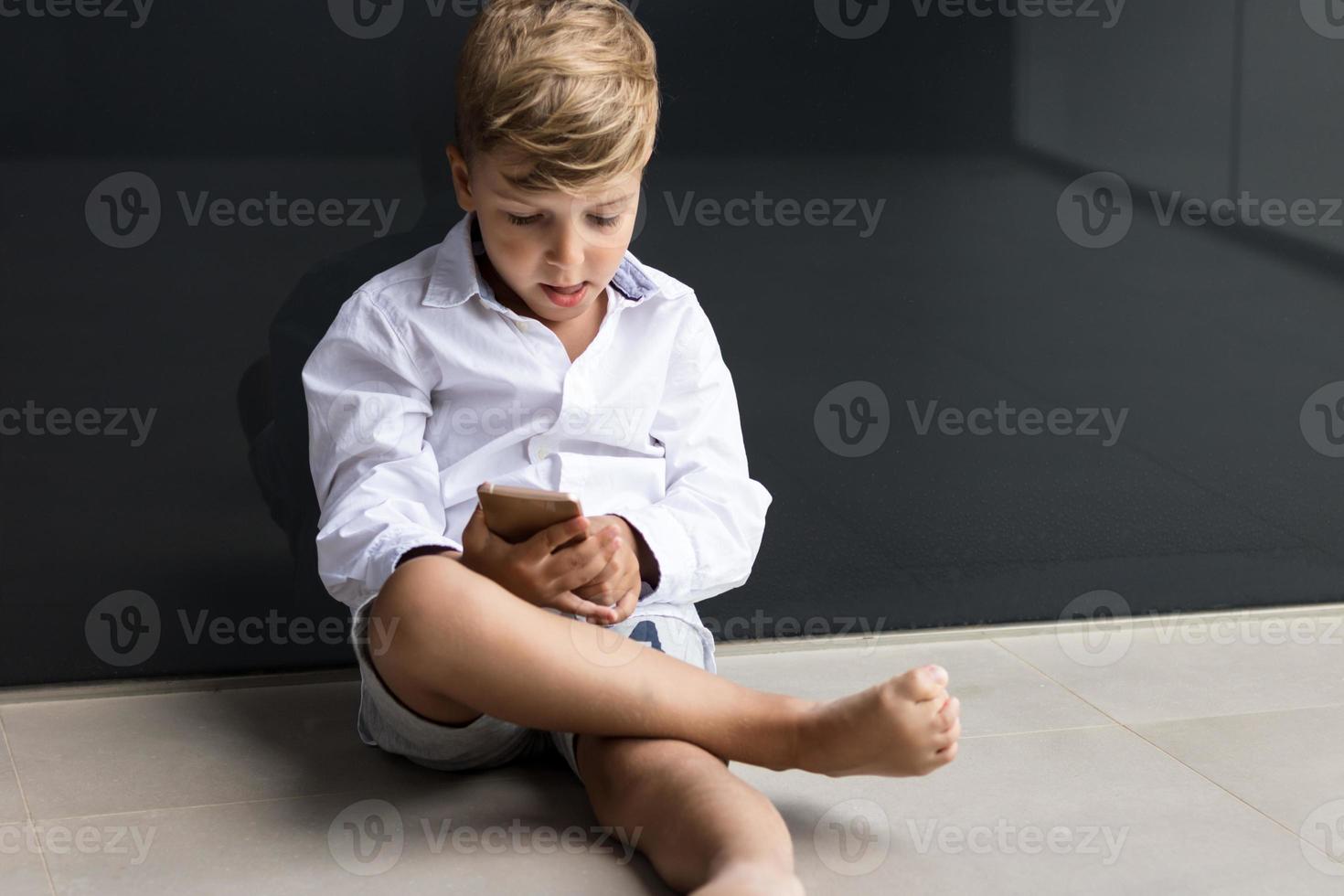 Little boy playing games on smart phone. photo