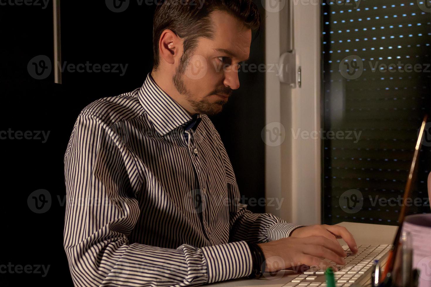 empresario adulto medio escribiendo un correo electrónico mientras trabaja hasta tarde. foto