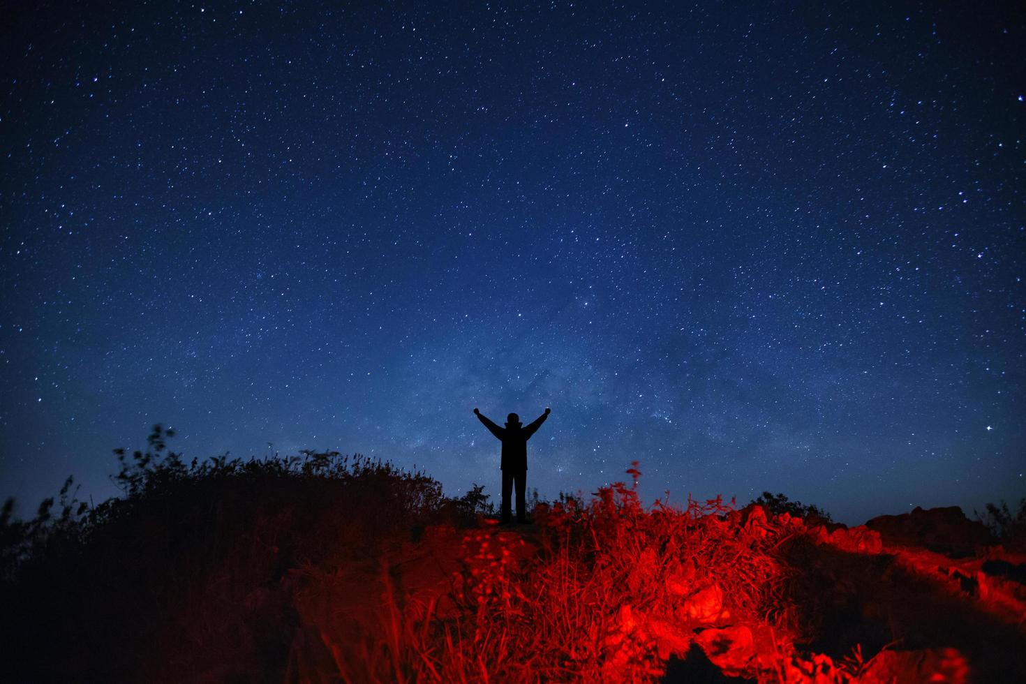 paisaje con galaxia de la vía láctea, cielo nocturno estrellado con estrellas y silueta de un hombre deportivo de pie con los brazos levantados en la alta montaña. foto