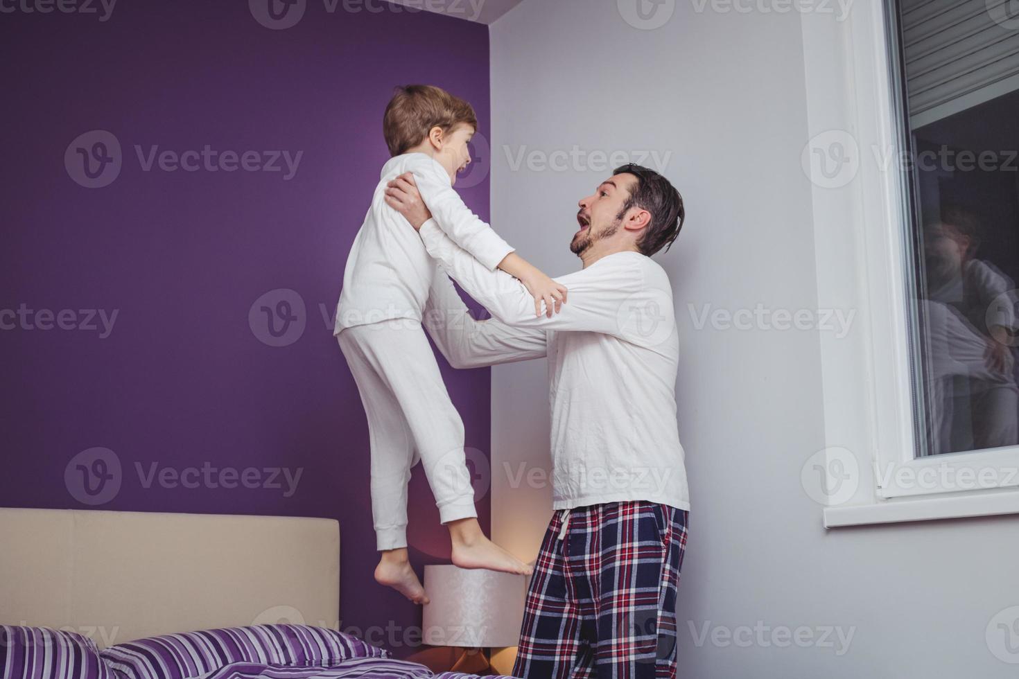 Happy father and son playing in bedroom and having fun in the evening. photo