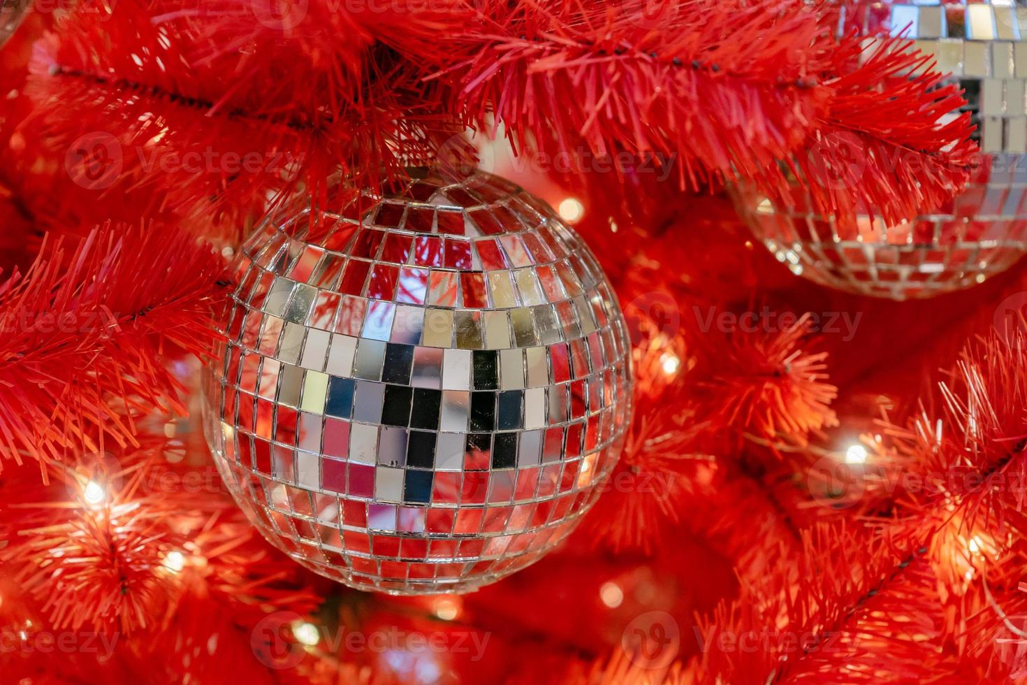 Silver disco ball on a red christmas tree. Festive new year background. photo
