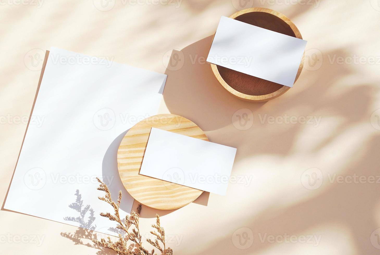 Flat lay of branding identity business name card on yellow background with flower and wooden container, light and shadow shape leaves, minimal concept for design photo