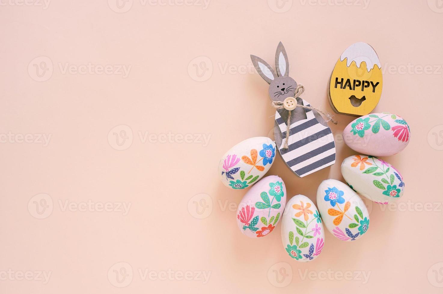 Happy Easter concept with wooden bunny and colorful easter eggs on yellow background. Top view with copy space photo