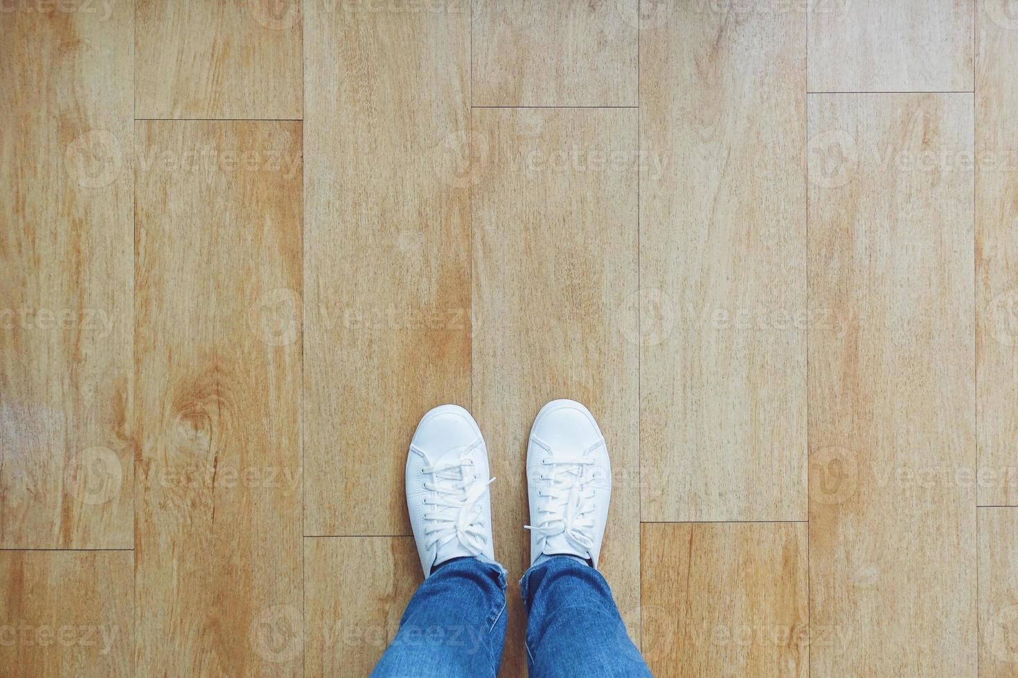 Selfie of feet in fashion sneakers on wooden floor background, top view with copy space photo