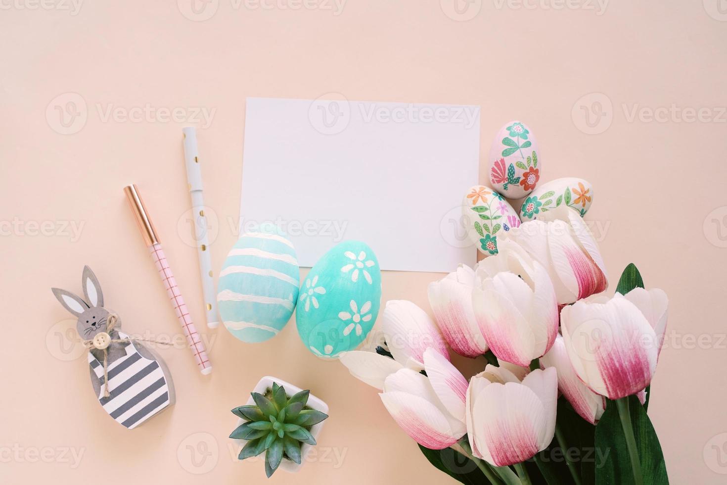 feliz concepto de pascua con tarjeta en blanco y coloridos huevos de pascua y tulipanes rosas. vista superior con espacio de copia foto