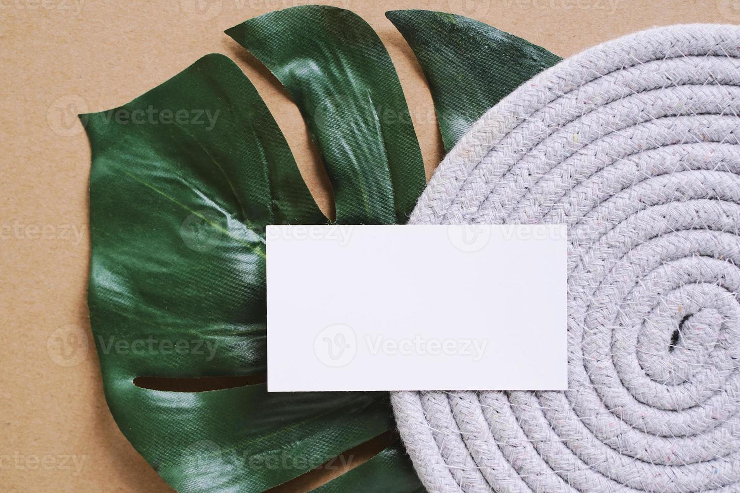 Flat lay of branding identity business name card on green plant leaf background, minimal and organic concept for design photo