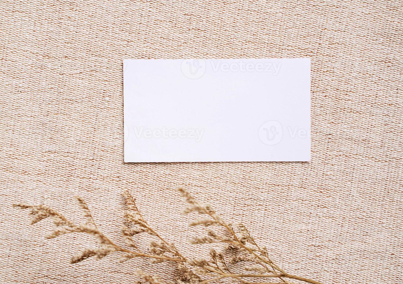 Flat lay of branding identity business name card on brown fabric background with flower, minimal concept for design photo