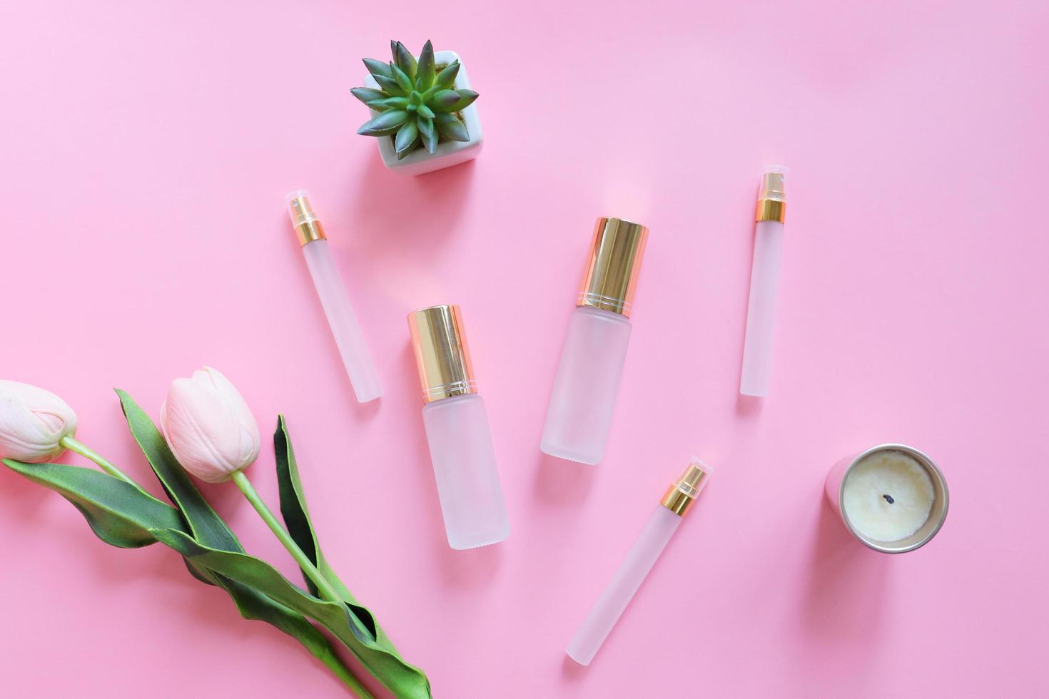 Flat lay of beauty skincare products for mock up in minimal style with plant and flower on pink background photo