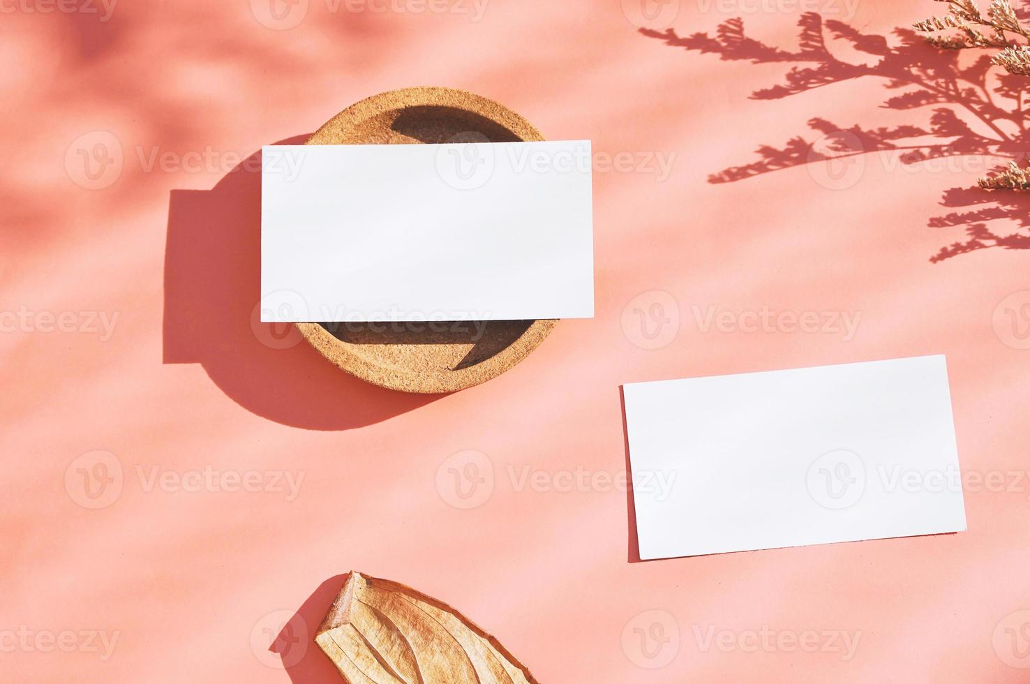 Flat lay of branding identity business name card on orange background with dry flower and leaf, minimal light and shadow concept for design, autumn season style photo