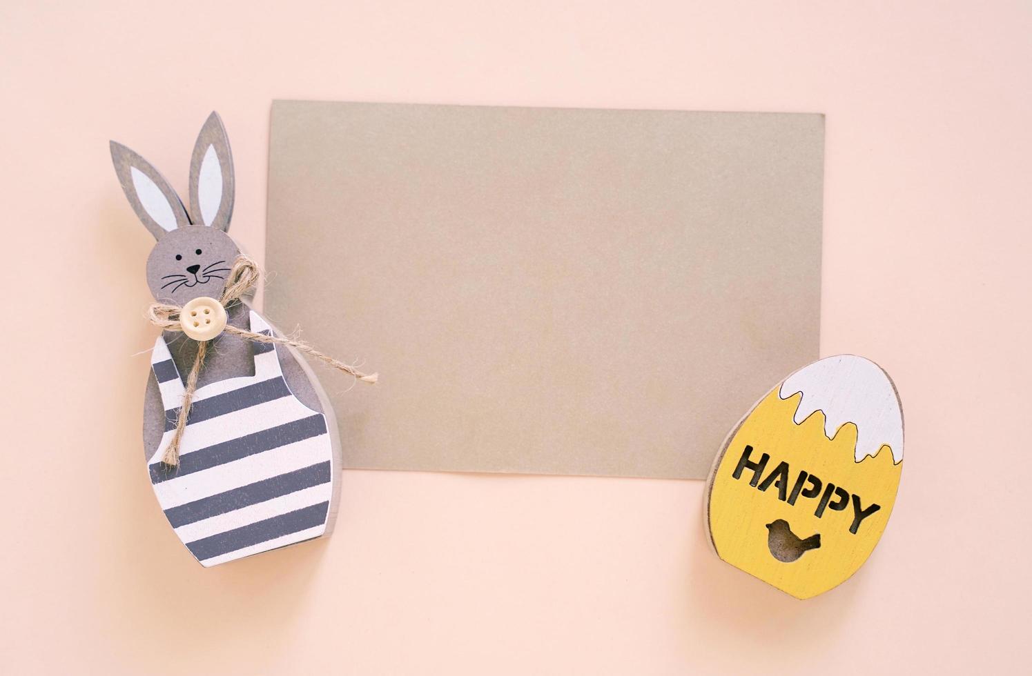 Happy Easter concept with blank card, wooden bunny and colorful easter eggs on yellow background. Top view with copy space photo