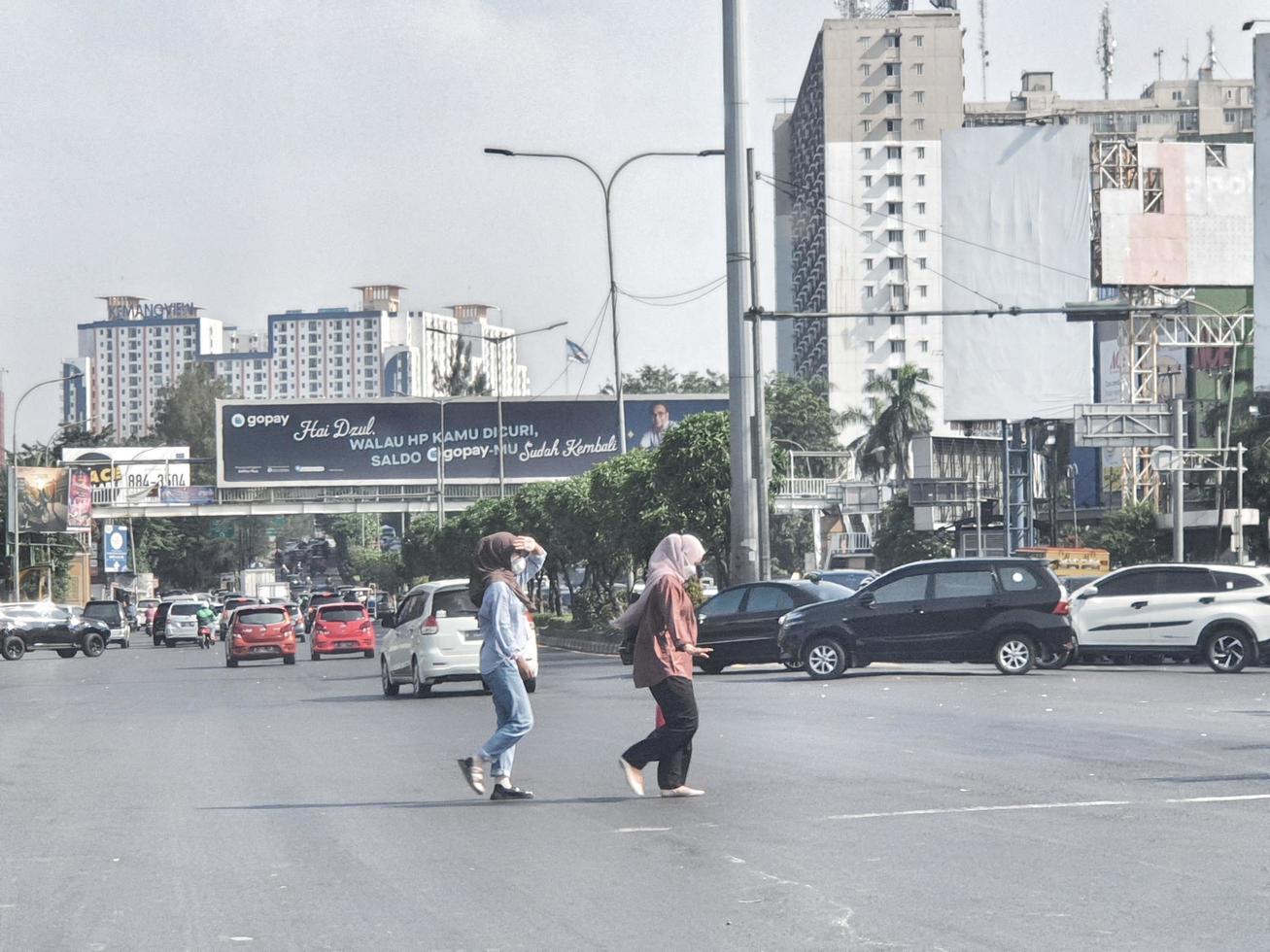 West Java, Indonesia on July 2022. Two Muslim women in headscarves are crossing the road not in the right place. photo