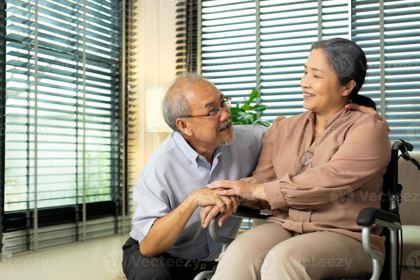 Senior Elderly Couple hold hands together after retirement, Husband wife person take care each other in romantic time with smile happy enjoy. Asian grandparent sit on wheel chair looking, copy space photo