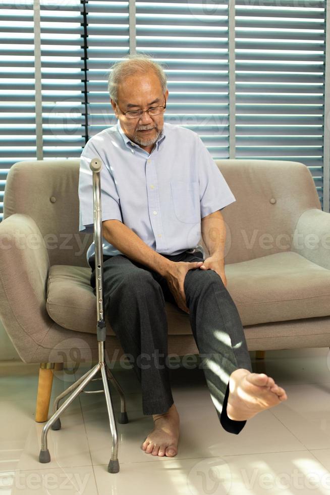 Grandfather unhappy health from pain Knee injury. Senior Elderly man has problem on joint knee leg and suffer ache health care problem when sitting and need walker staff to support help, copy space photo
