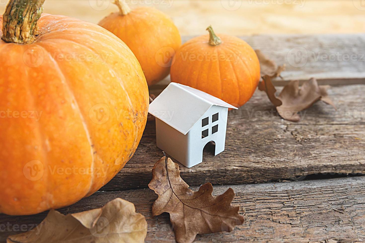 Autumnal Background. Toy house and pumpkin on wooden background. Thanksgiving banner copy space. Hygge mood, change of seasons concept. Hello Autumn with family Halloween party. photo