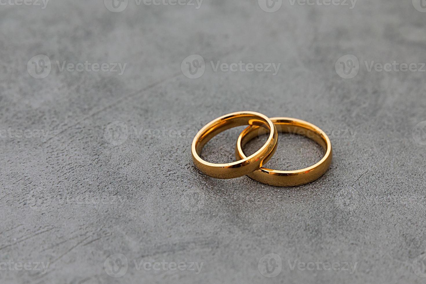Will you marry me. Two golden wedding rings on concrete stone grey background. Engagement marriage proposal wedding concept. Banner on wedding day with copy space. Wedding day details. photo