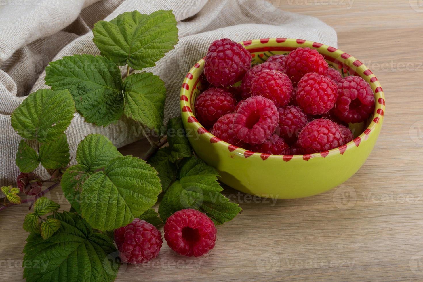 Fresh raspberry in a bowl on wooden background photo