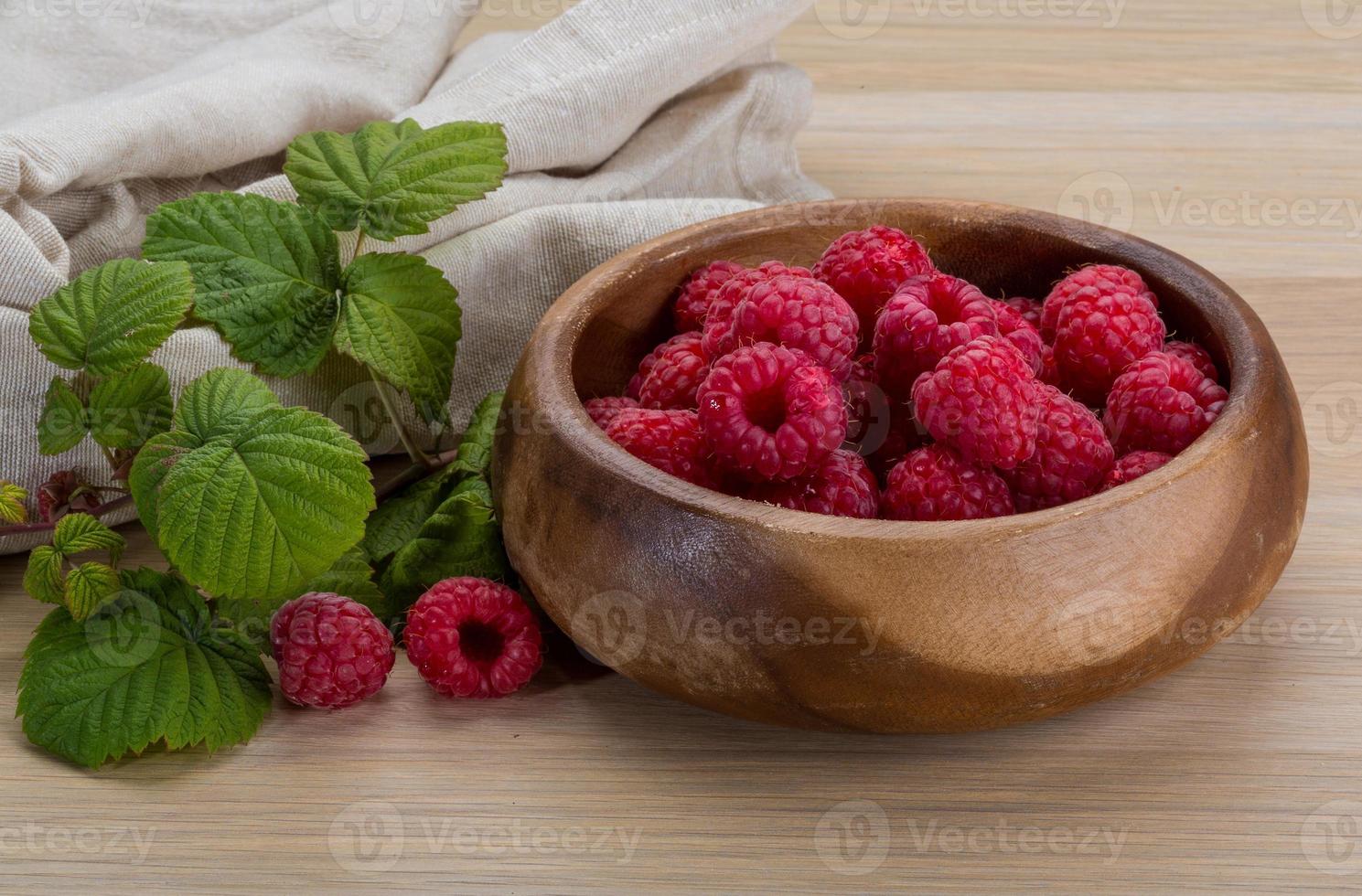 Fresh raspberry in a bowl on wooden background photo