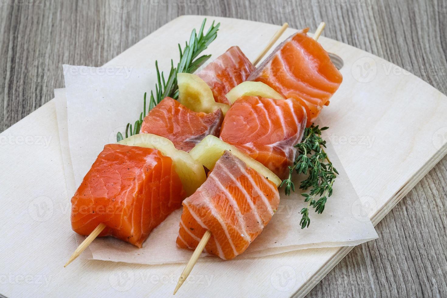 Salmon skewer on wooden board and wooden background photo