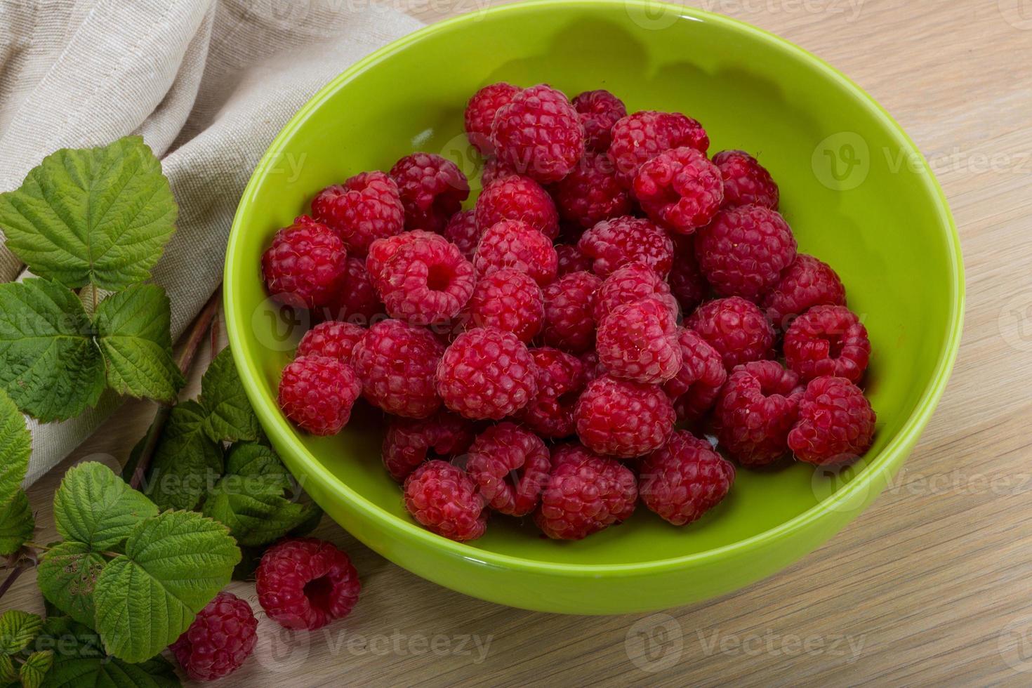 Fresh raspberry in a bowl on wooden background photo