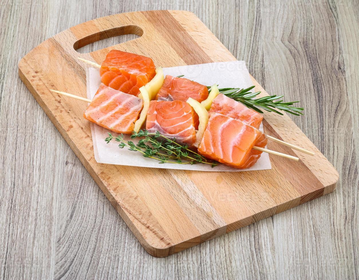 brocheta de salmón sobre tablero de madera y fondo de madera foto