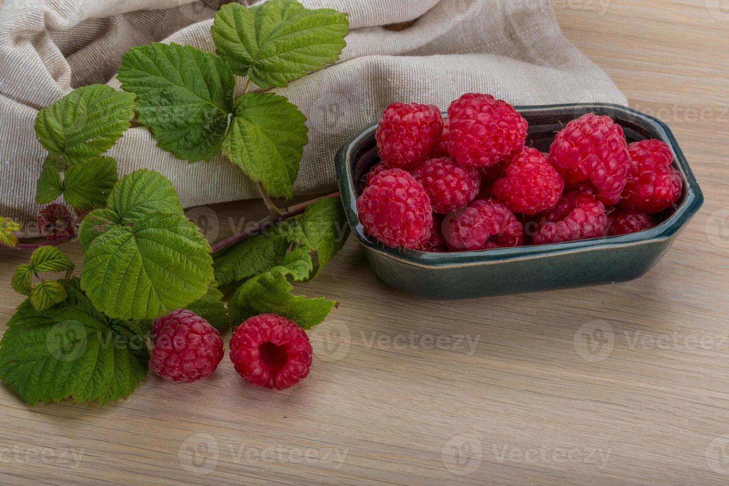 Fresh raspberry in a bowl on wooden background photo