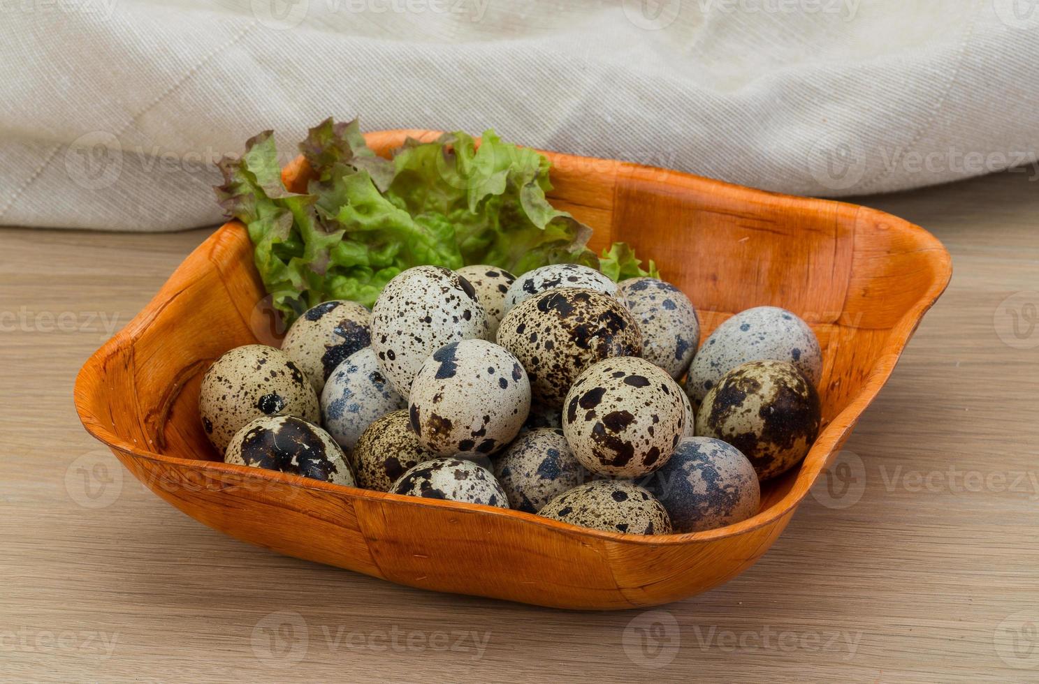 Quail eggs in a bowl on wooden background photo