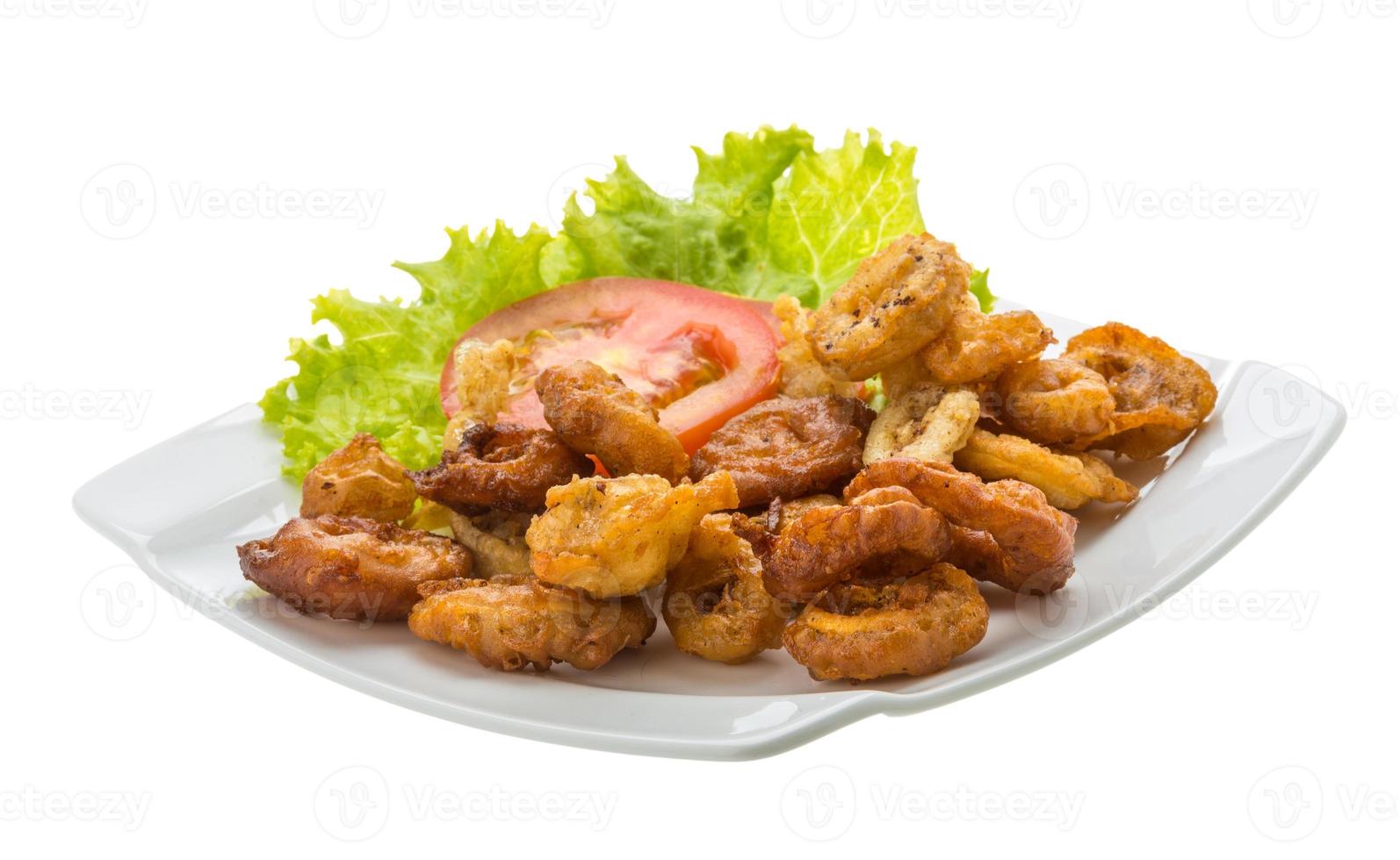 Anillos de calamar fritos en el plato y fondo blanco. foto