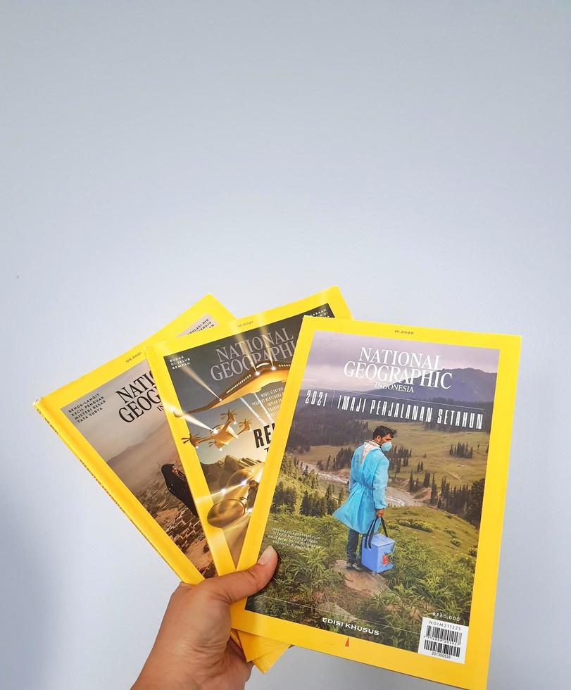 West Java, Indonesia on July 2022. A hand holds the Indonesian version of the National Geographic magazine. The first version of National Geographic Indonesia was published in April 2005 until now. photo