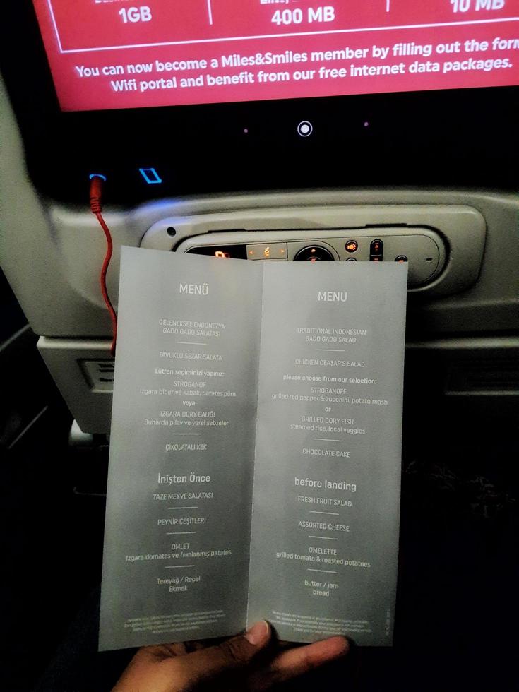 Istanbul, Turkey on July 2022. Two hands are holding a flight meal menu from Turkish Airline. photo