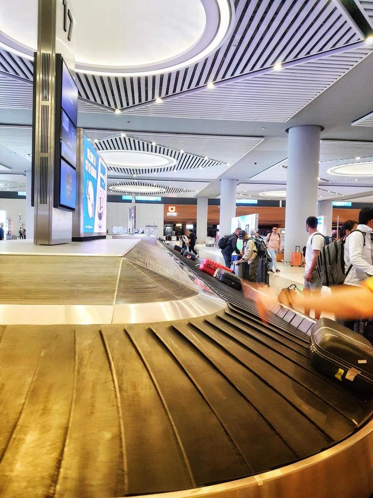 Istanbul, Turkey in July 2022. Tourists picking up their suitcases or luggage on a conveyor belt in the Istanbul international airport. photo