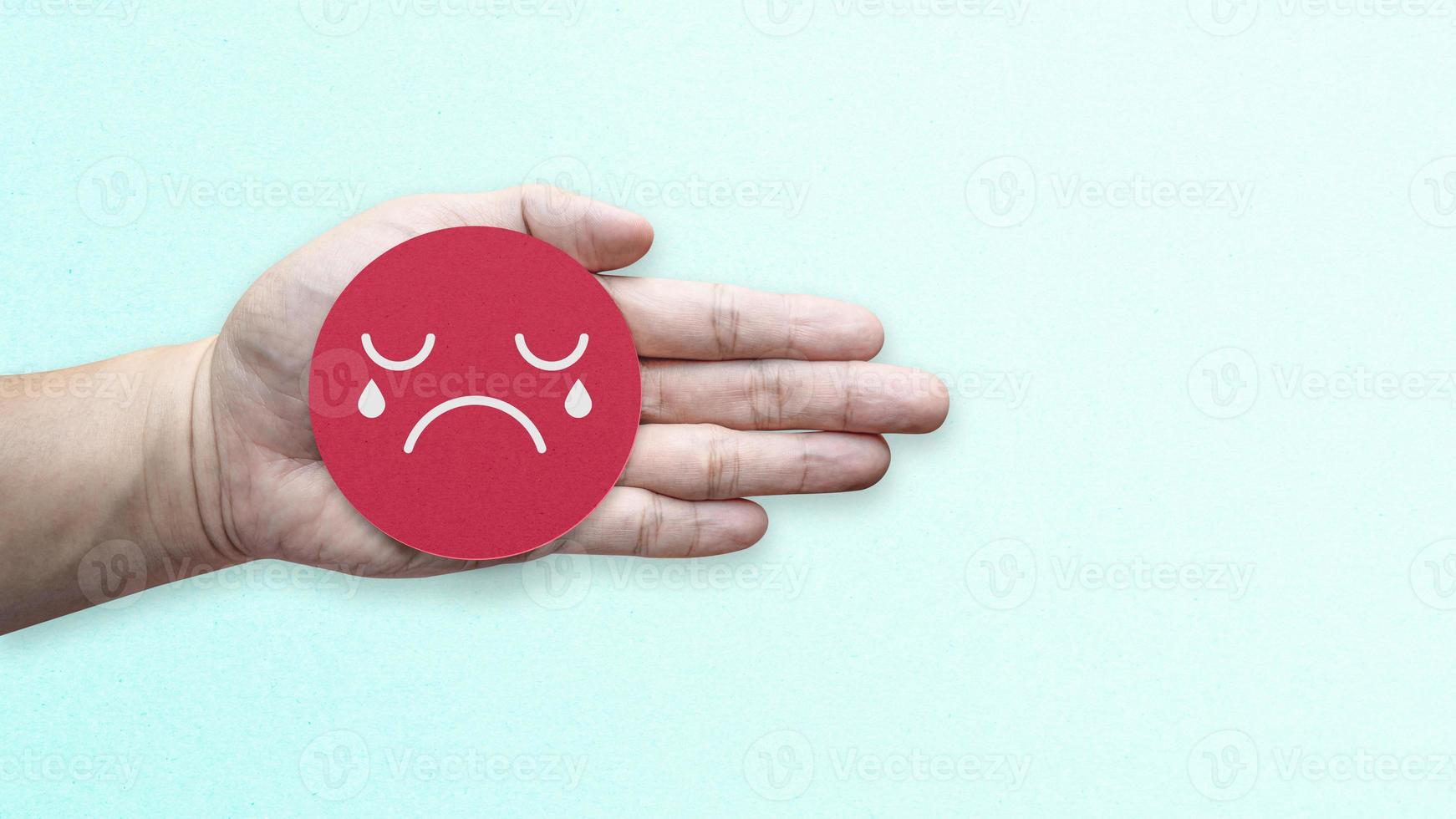 Hand holding red paper with unhappy emotion face. Customer review satisfaction feedback survey. photo