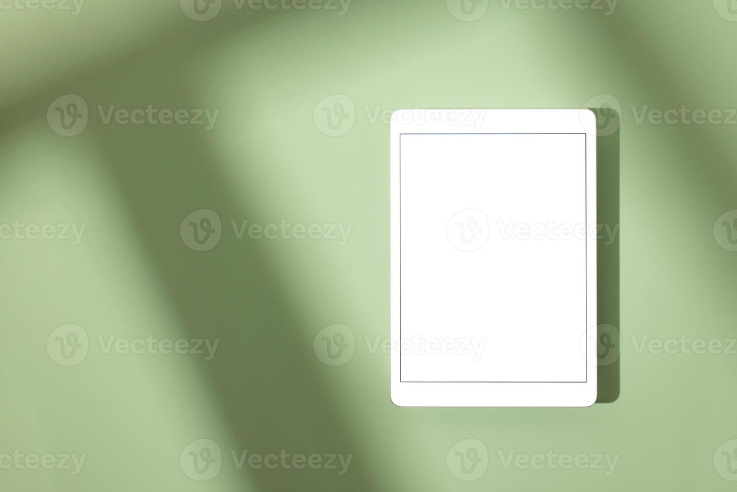 Blank screen tablet mock up and shadow on green pastel background. Copy space. Mock up template. Business communication. Isolated object. Spring decoration. photo