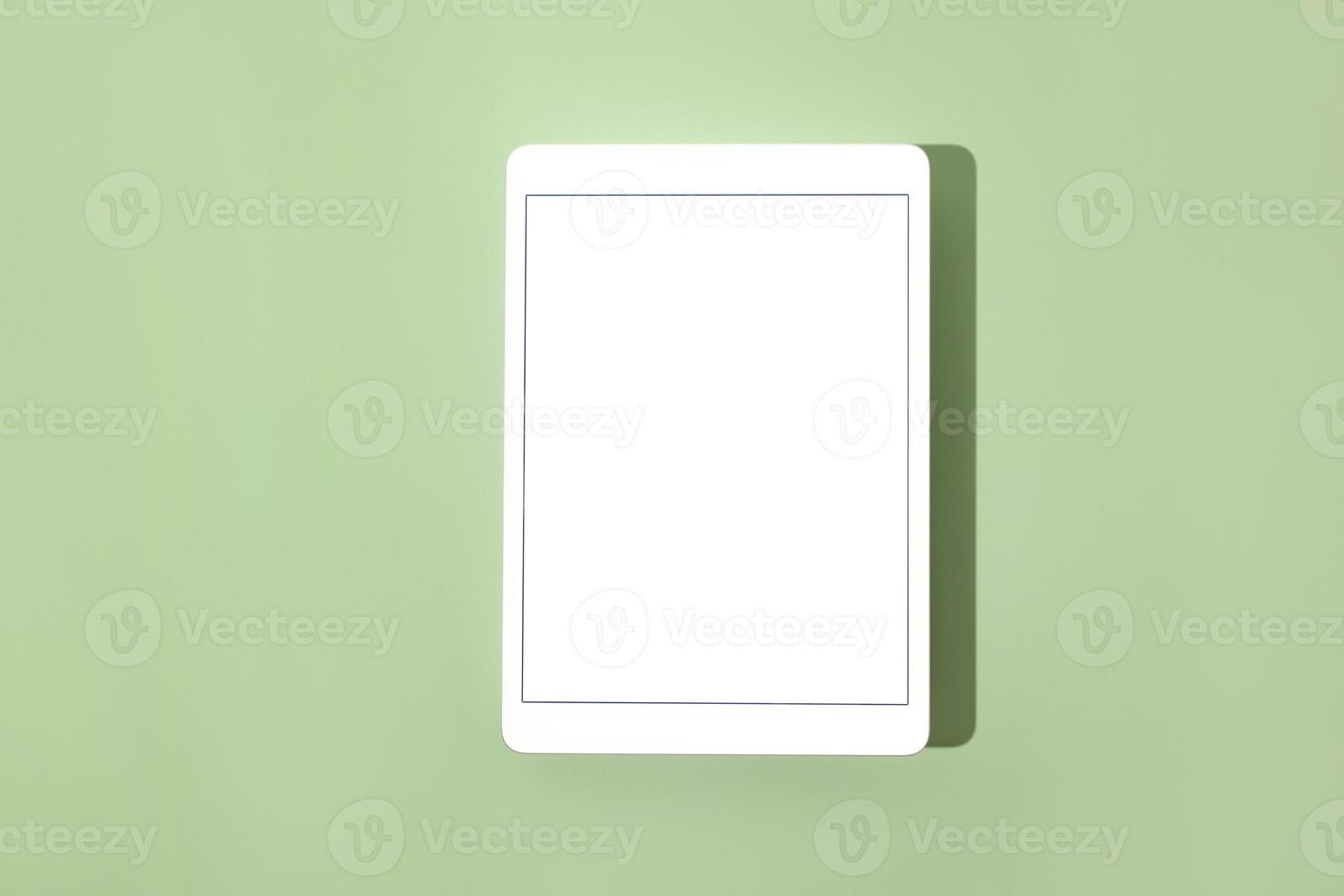 Blank screen tablet mock up and shadow on green pastel background. Copy space. Mock up template. Business communication. Isolated object. Spring decoration. photo