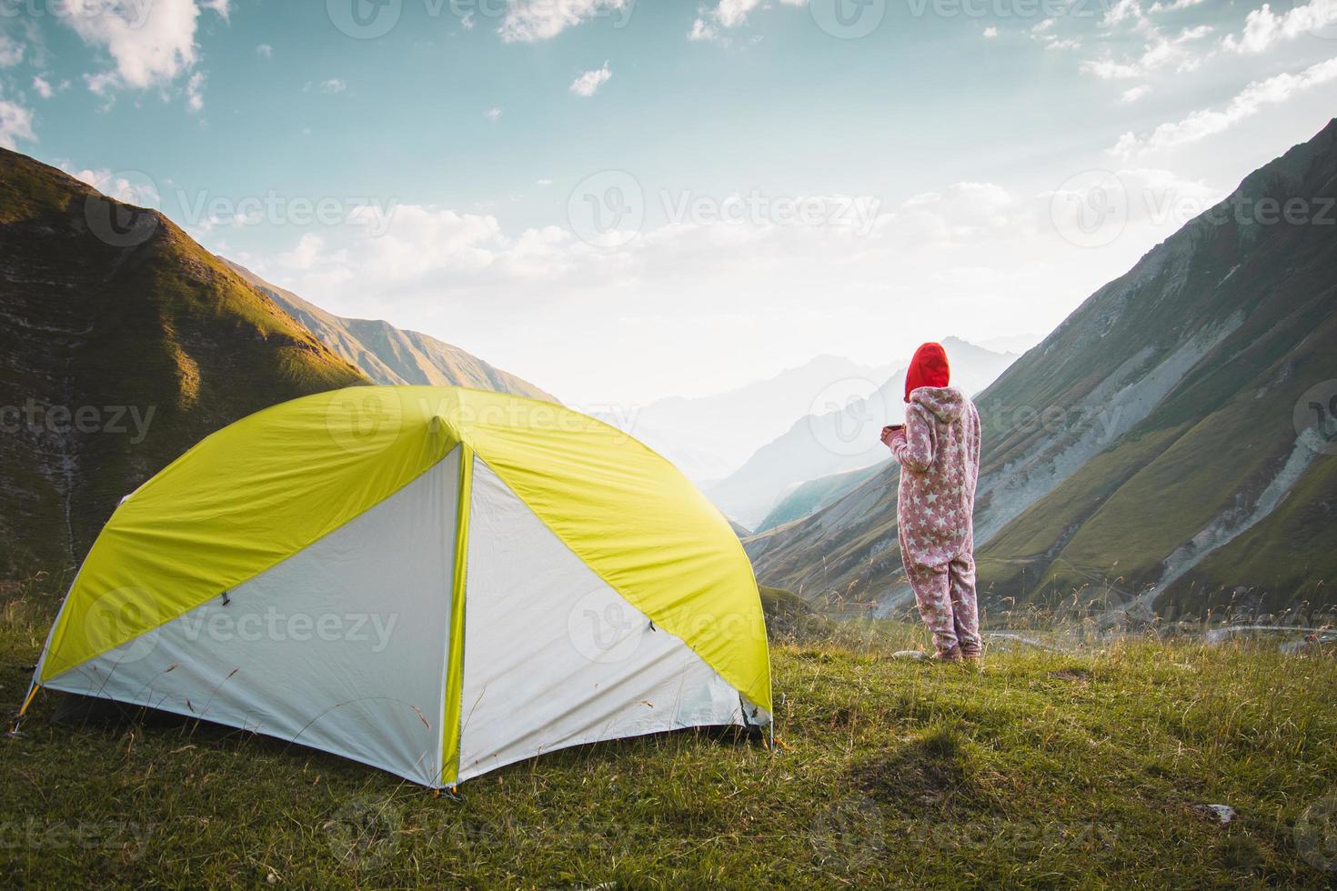 Back view thoughtful female caucasian in pyjamas stand on viewpoint drink fresh coffee in nature enjoy scenic mountains panorama in early morning sunrise alone. photo