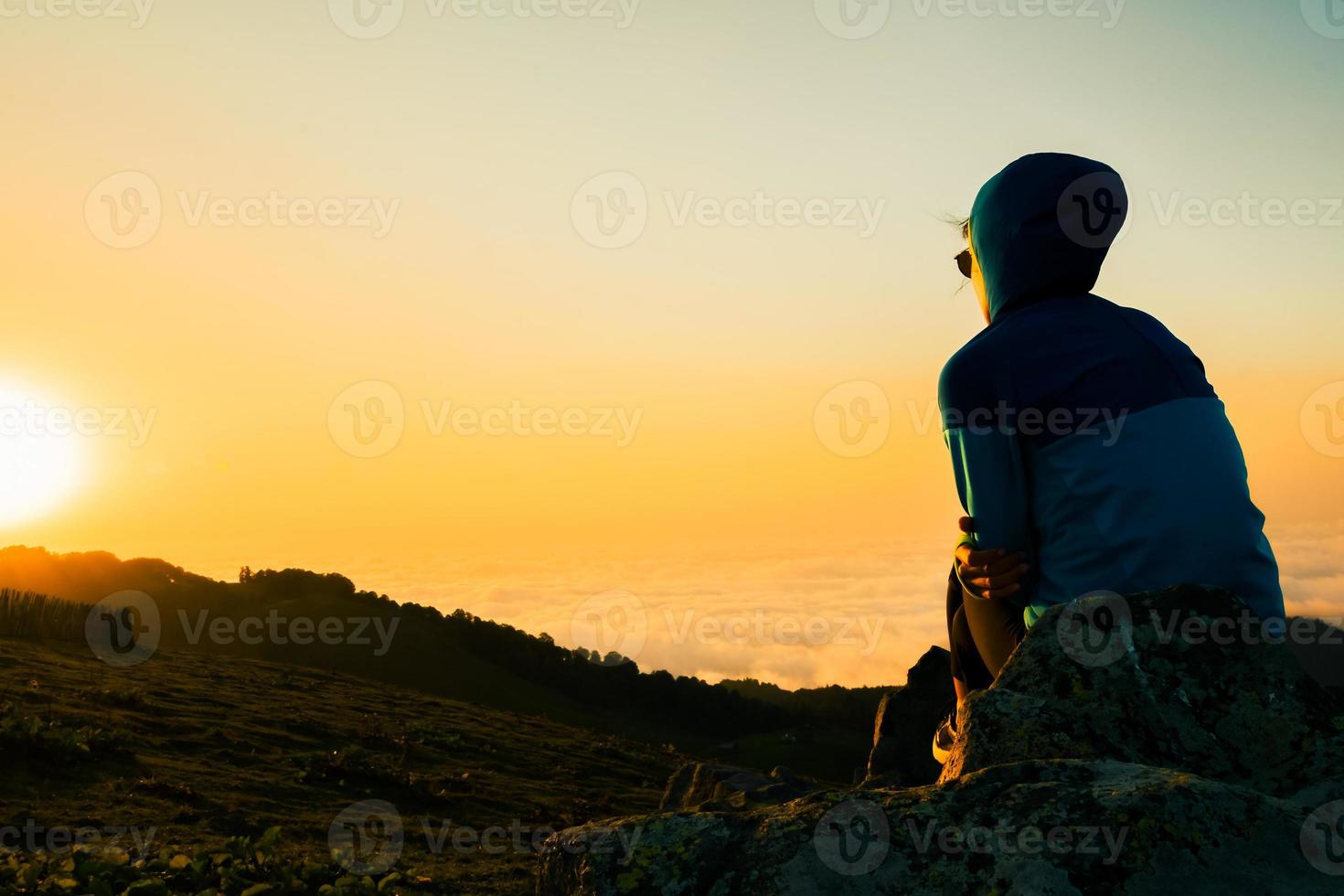 Lonely happy woman portrait watch sunrise. Carefree tourist woman looking at sun enjoying landscape. Girl traveler on top of mountain in rays of sunset. Hiker is enjoying nature photo