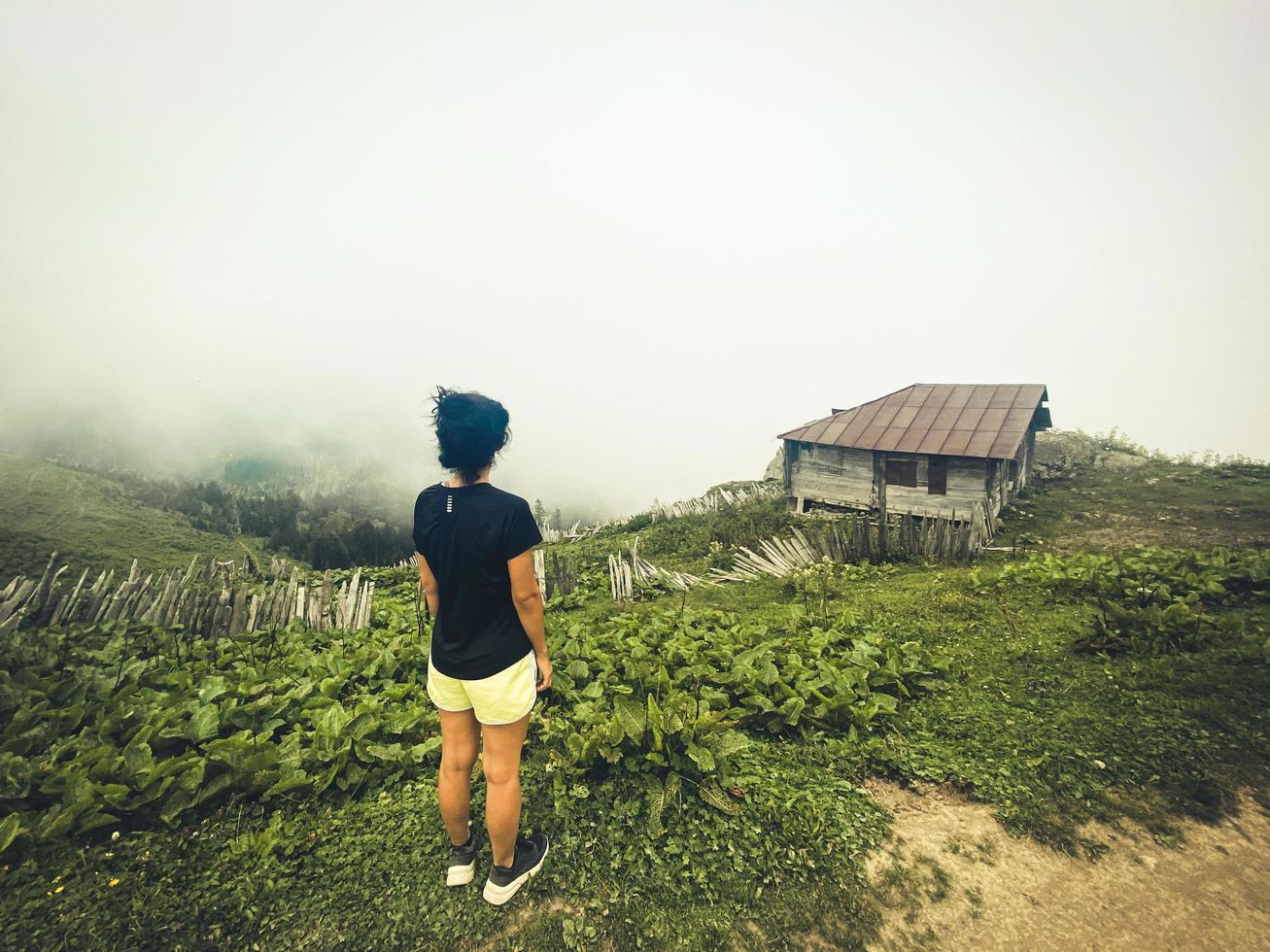 Beautiful female traveler take photo of local culture in Georgia. Villager pick flower for medical use in summer fields