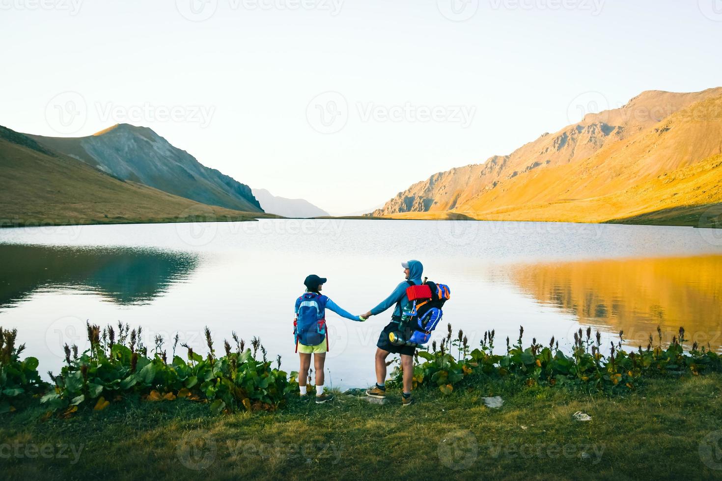 Caucasian hiker couple stand happy together outdoors by scenic black rock lake in Georgia. Tourist enjoy active holidays in nature in love adventure photo