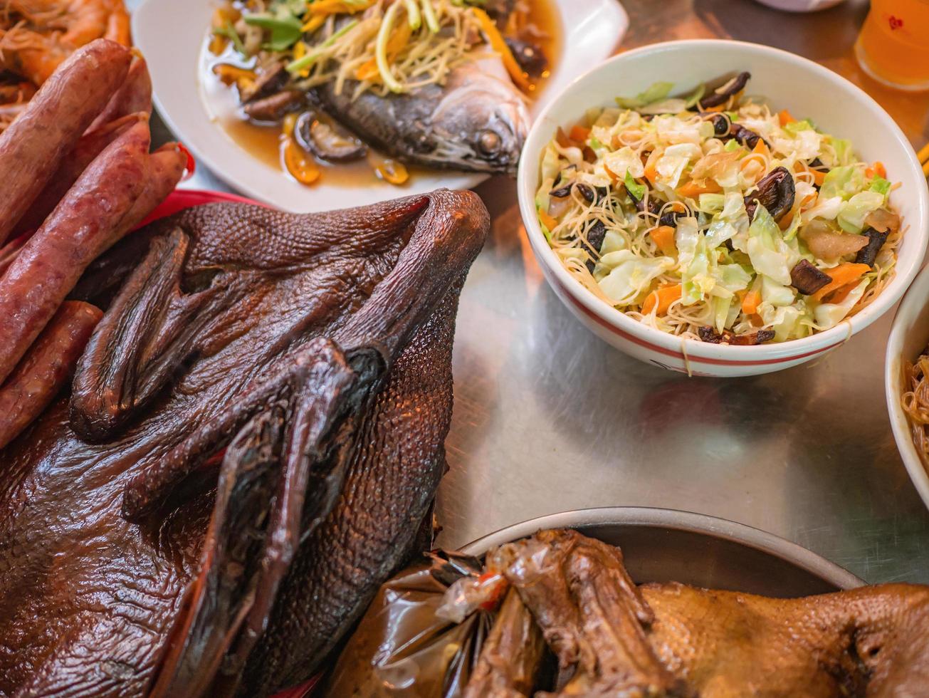 comida para rezar respeto al predecesor en la cultura china y cuando llegue el año nuevo chino. pato hervido, pescado al vapor en la mesa de metal foto