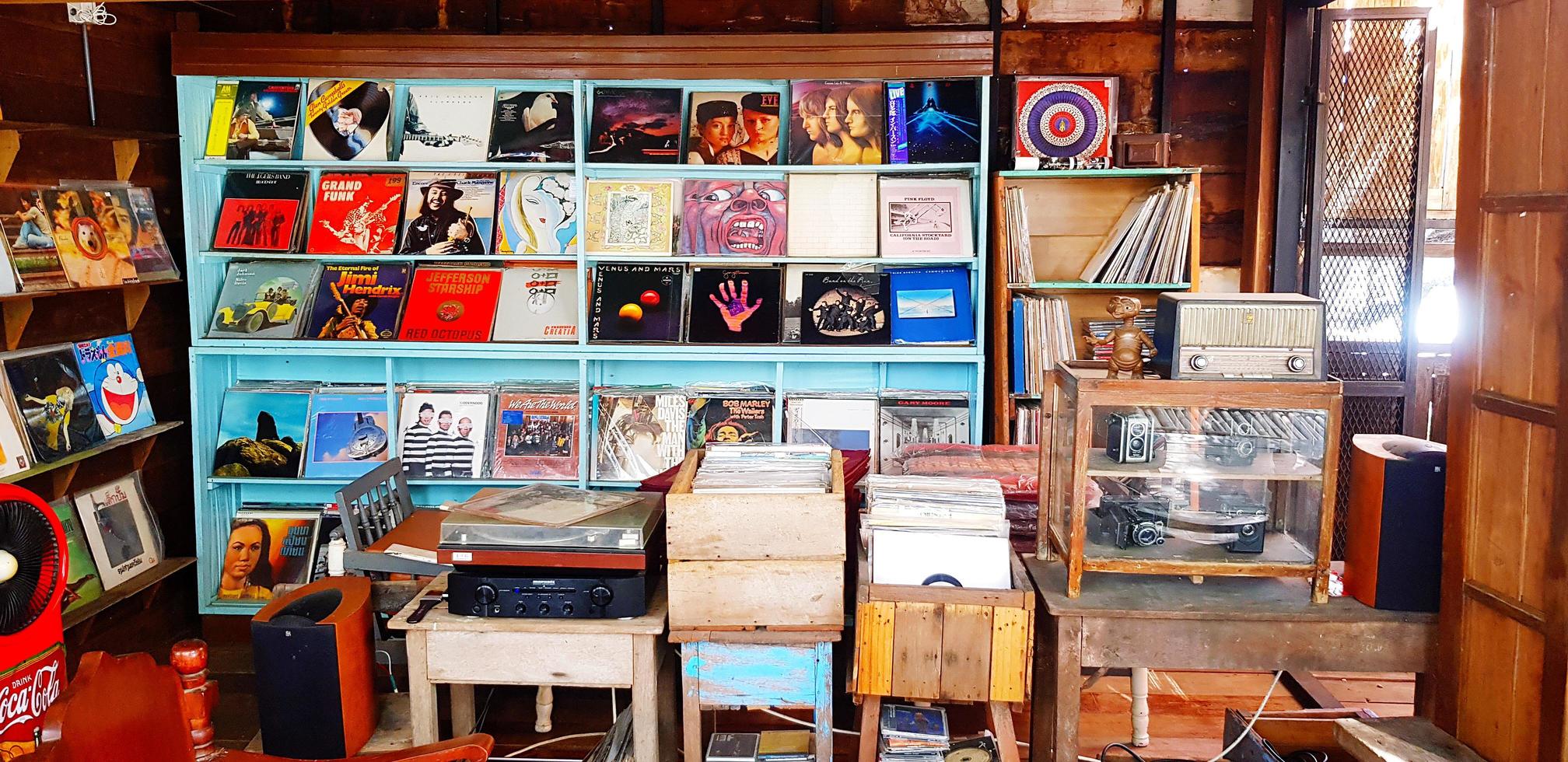 Samut Sakhon, Thailand  July 15, 2022 Many record or dish put on wooden shelf for sale. Collection of Vintage object and classic camera in glass cabinet. photo