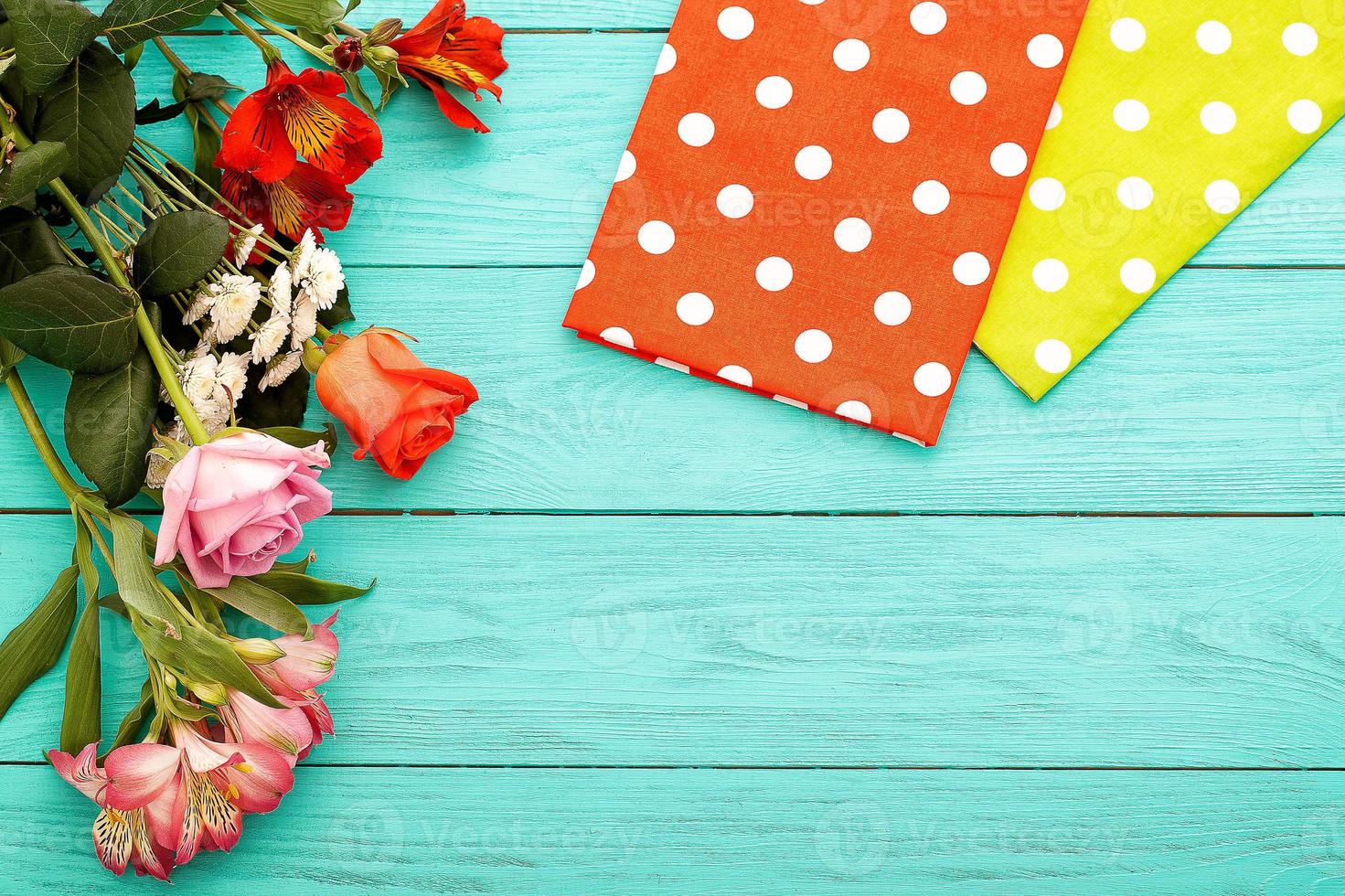 Frame of flowers and towels in polka dots on blue wooden background. Top view and selective focus. Copy space photo