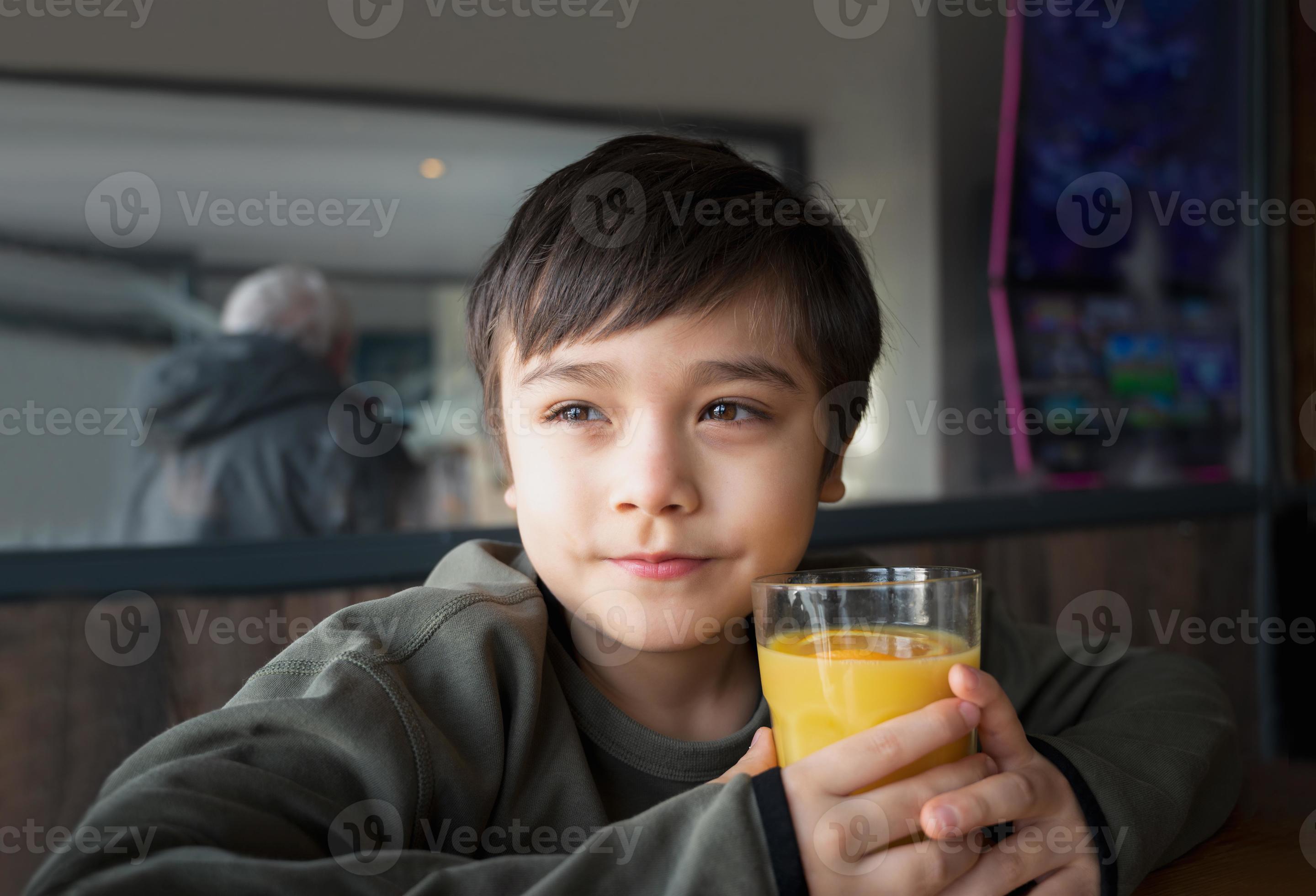 Portrait Young kid drinking fresh orange juice for breakfast in cafe
