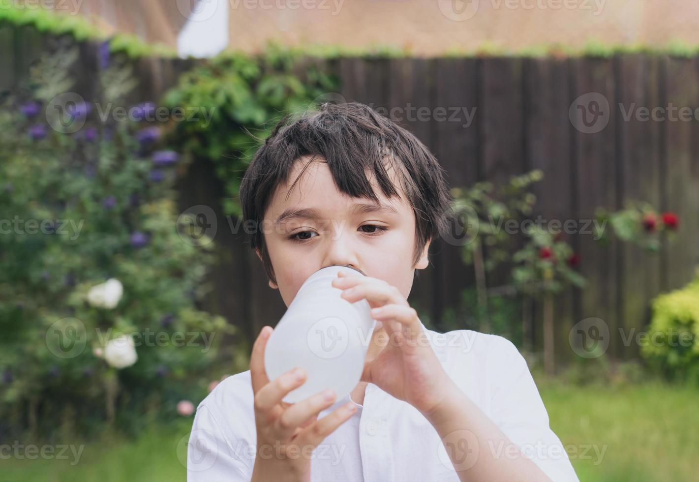 Kid drinking water, Thirsty boy holding a bottle of water, Child drinking water while playing in the garden, World Children day, World Environment Day photo